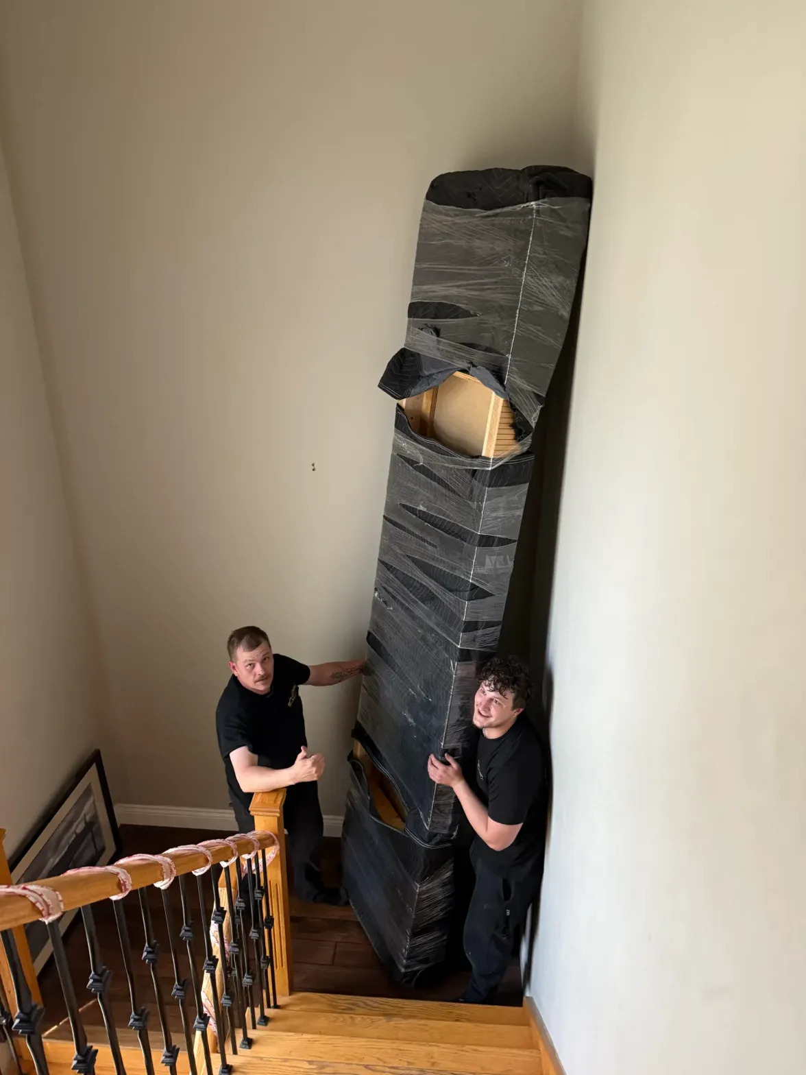 two-men-moving-wrapped-furniture-upstairs